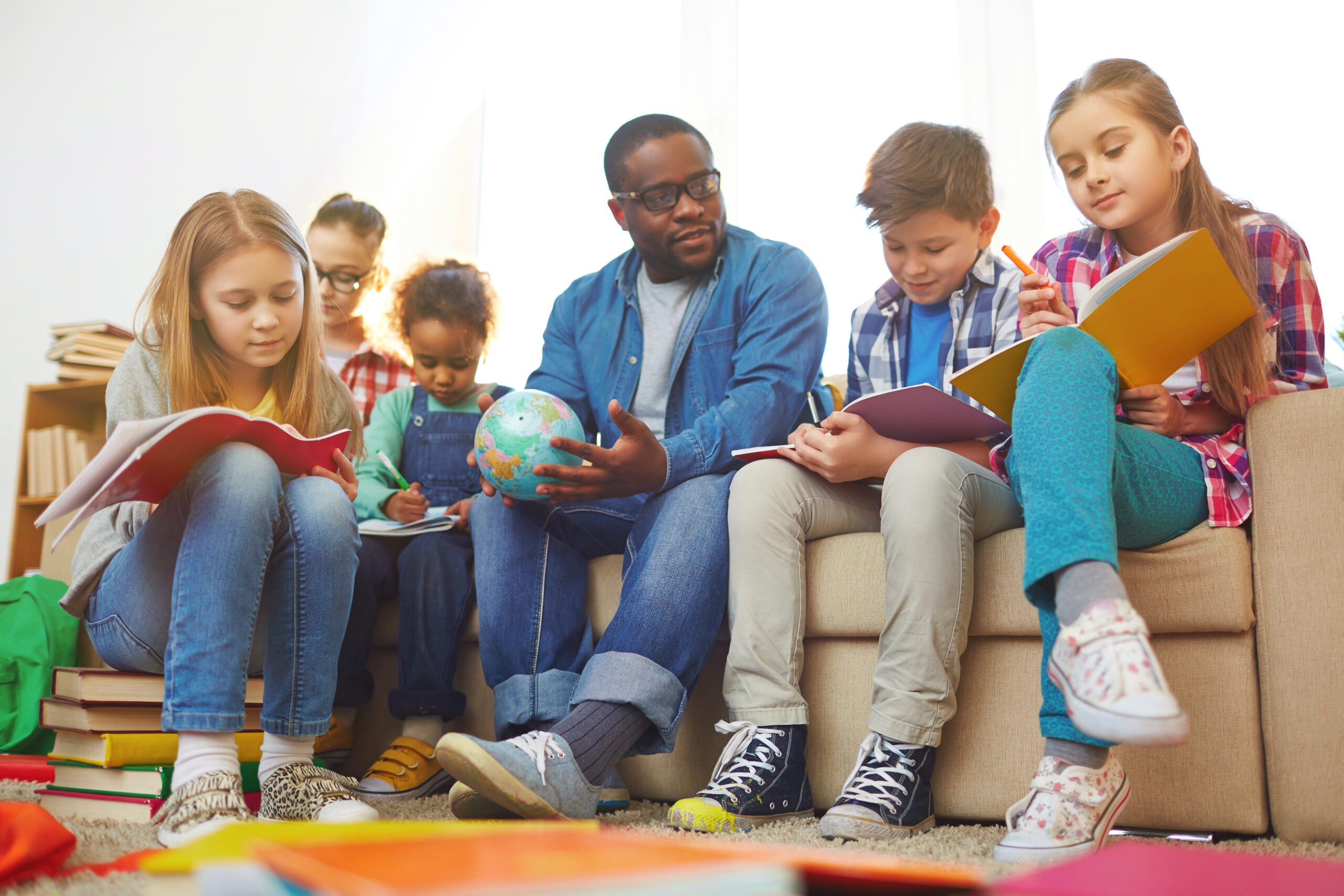Children sitting on sofa with teacher and writing